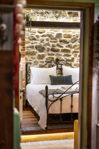 a bedroom with a bed with a stone wall at Archontiko Theofanous in Tríkala