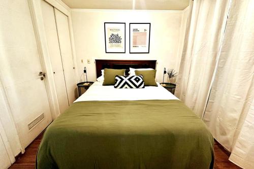 a bedroom with a large bed with a green blanket at Santiago Urbano Apartments - Centric Santiago in Santiago