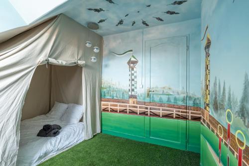 une chambre d'enfant avec un lit à baldaquin et une fresque murale dans l'établissement La Tanière Éternelle - Repère de sorciers à Boulogne Sur Mer, à Boulogne-sur-Mer