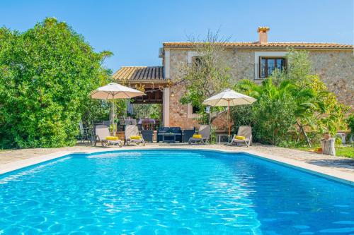 a swimming pool with chairs and umbrellas in front of a house at 126 Finca Son Tresco ETV4382 by Mallorca Charme in Búger