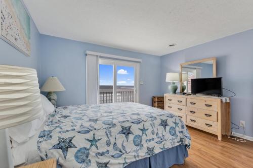 a bedroom with a bed and a dresser and a window at Ocean Dunes 306 by Carolina Beach Realty in Kure Beach
