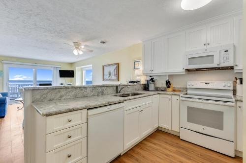 a kitchen with white cabinets and white appliances at Ocean Dunes 306 by Carolina Beach Realty in Kure Beach