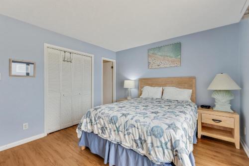 a bedroom with a bed and a table with a lamp at Ocean Dunes 306 by Carolina Beach Realty in Kure Beach