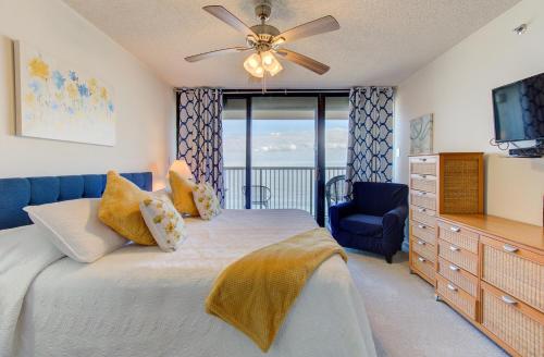 a bedroom with a bed with a ceiling fan and a balcony at Pelican Watch in Carolina Beach