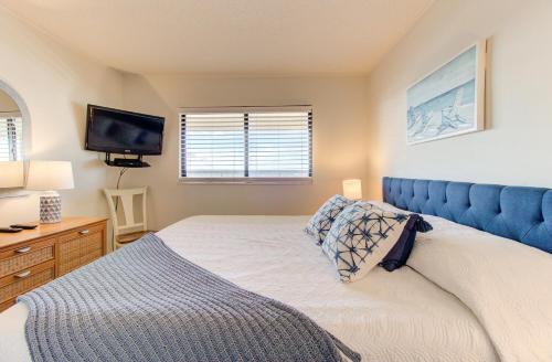 a bedroom with a bed with a blue headboard and a television at Pelican Watch in Carolina Beach