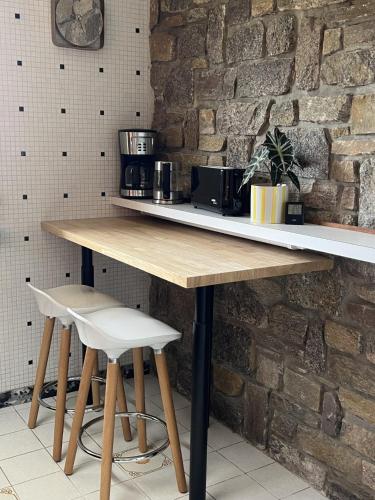 une table en bois avec deux tabourets devant un mur de briques dans l'établissement Villa Angeli, à Les Sables-dʼOlonne