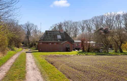 a dirt road in front of a red barn at 4 Bedroom Awesome Home In Rudkøbing in Rudkøbing