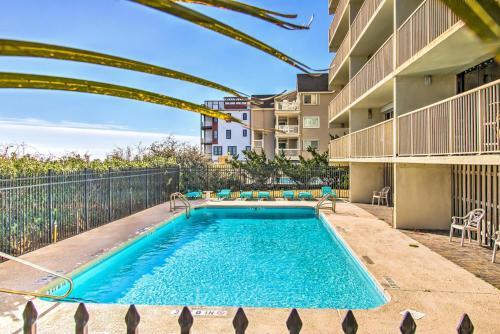 a swimming pool with chairs and a building at Pelican Watch 706: Sea You Next Time by Carolina Beach Realty in Carolina Beach