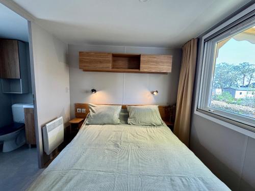 une petite chambre avec un lit et une fenêtre dans l'établissement Les viviers jours de rêves, à Lège-Cap-Ferret