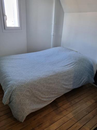 Ce lit se trouve dans une chambre blanche dotée de parquet. dans l'établissement Bohemian cosy flat, à Paris