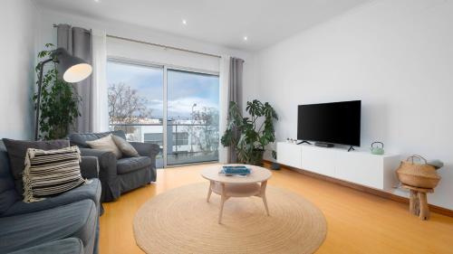 a living room with a couch and a tv and a table at Paim Apartments in Ponta Delgada