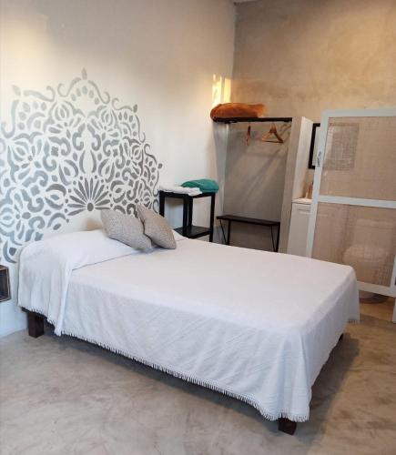 a bedroom with a bed with a white wall at Casa Ha Hostal in Mérida