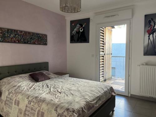 - une chambre avec un lit et une porte donnant sur un balcon dans l'établissement 3 pièces central au pied de la promenade du paillon, à Nice