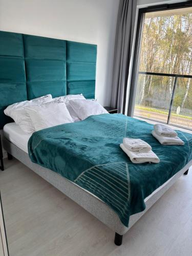 - un lit avec serviettes dans une chambre avec fenêtre dans l'établissement Apartament Słoneczny AKTENA Shellter Rogowo, à Rogowo