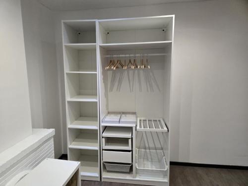 a white closet with white shelves and hangers at Yaël House in Brussels