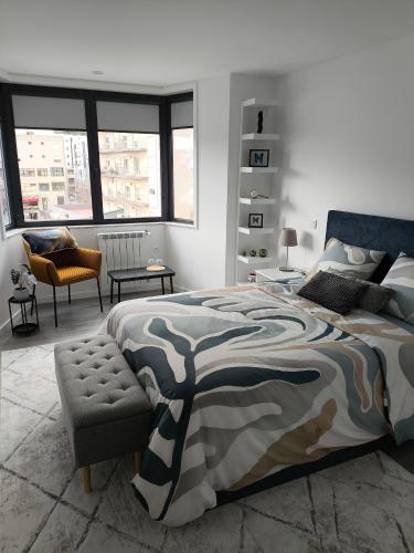 a bedroom with a bed and a chair and windows at Alojamento Local Mariposa Azul in Valença