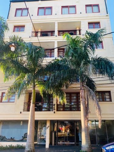 a building with palm trees in front of it at THE HEIRS Departamentos in Posadas