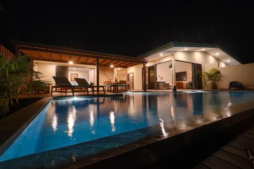 a swimming pool in front of a house at night at Moorea Beach Villas in Haapiti