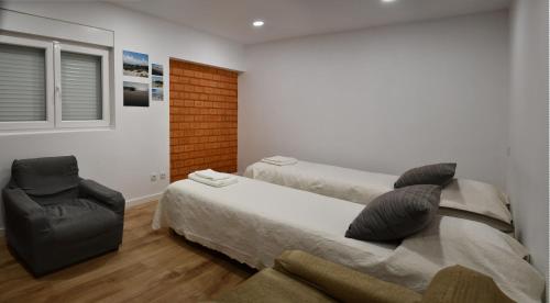 a bedroom with two beds and a chair in it at Casa do Avô Ezequiel in Vendas Novas