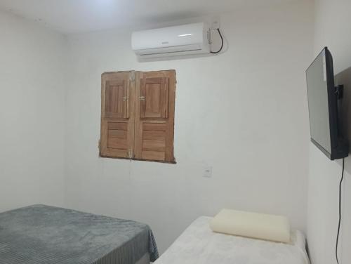 a room with two beds and a tv and a cabinet at Pousada dos Artistas in Japaratinga