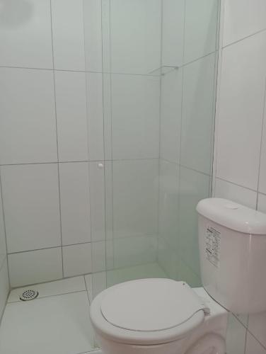 a bathroom with a toilet and a white tiled wall at Pousada dos Artistas in Japaratinga