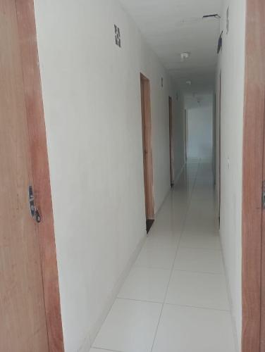 an empty hallway with a door and a white floor at Pousada dos Artistas in Japaratinga