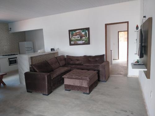 a living room with a brown couch and a tv at Casa Praia Milagres in São Miguel dos Milagres