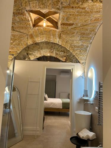 ein Schlafzimmer mit einem Bett in einem Zimmer mit einer Steinmauer in der Unterkunft Addimura rooms in Palermo