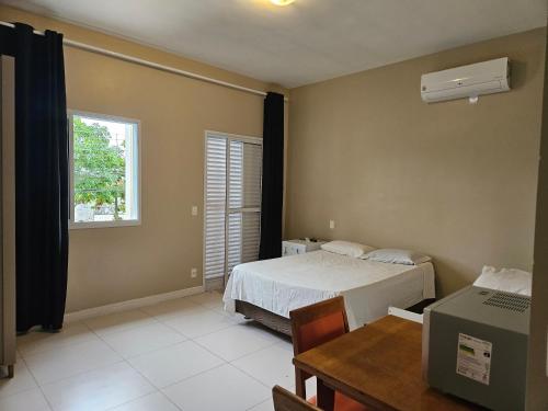 a bedroom with a bed and a desk and a window at Suíte privativa próxima ao Sesc 1 in Bertioga