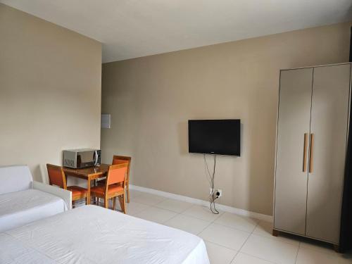 ein Schlafzimmer mit einem Bett, einem Tisch und einem Fernseher in der Unterkunft Suíte privativa próxima ao Sesc 1 in Bertioga