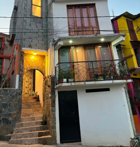 a white house with a black door and stairs at verde amanecer in Xilitla