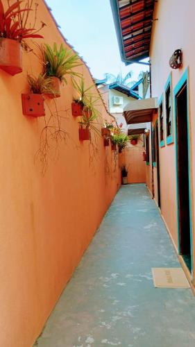 an alley with potted plants on the side of a building at Encanto Mada´s Itamambuca in Ubatuba