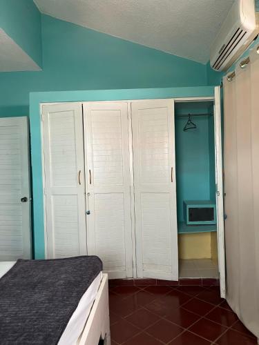 a bedroom with blue walls and a bed with white cabinets at PLAYA BLANCA BED AND BREAKFAST in Bayahibe