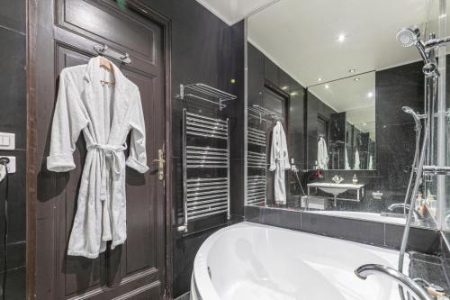 une salle de bain avec une baignoire et un grand miroir dans l'établissement Élysées vip, à Paris