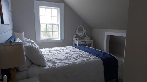 a white bedroom with a bed and a mirror at Cozy Harbour House in Isaacs Harbour