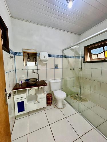 a bathroom with a toilet and a glass shower at Hospedagem Braga - acomodação domiciliar in Cunha