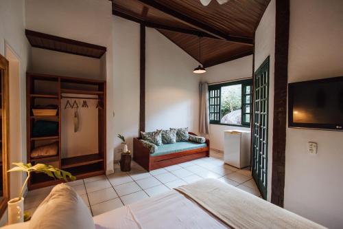 a living room with a couch and a tv at Pousada Vila das Pedras in Ilhabela