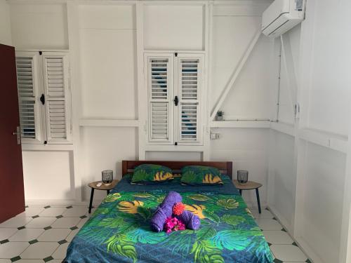 a bedroom with a bed with colorful blankets and pillows at Haut de villa 1chambre climatisée à 3min de l'habitation Clément in Le François