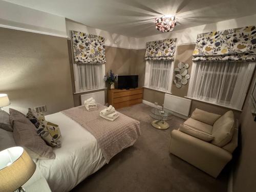 a bedroom with a bed and a chair and a television at Fadó & Tide Apartments in Filey
