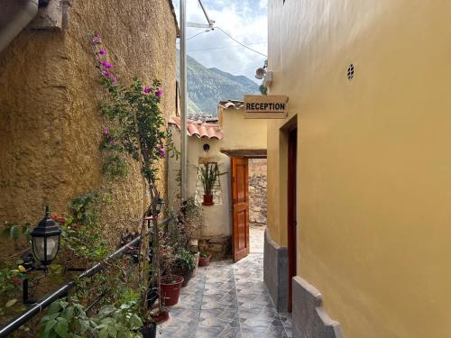 an alley with a door and some plants and flowers at Andenes del Inca Hotel in Ollantaytambo