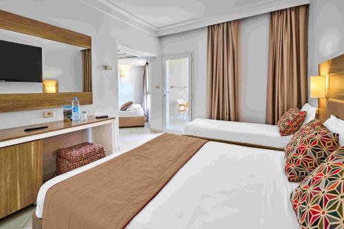 a hotel room with a large bed and a tv at TUI SUNEO Palm Beach Skanes - All Inclusive in Monastir