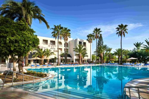a swimming pool with palm trees and a hotel at TUI SUNEO Palm Beach Skanes - All Inclusive in Monastir