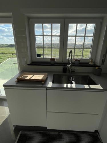 une cuisine avec un évier et deux fenêtres dans l'établissement Beachfront Costa Nova Villa - 3 BR Apartment, à Gafanha da Encarnação