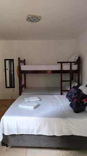 a bedroom with a large bed with white sheets at Pousada Preguiça in Canoa Quebrada