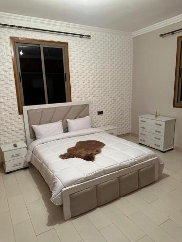 a white bedroom with a large bed with a brown animal on it at Villa haut standig 2000 m2 in Marrakesh