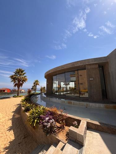 a building on the beach with flowers in front of it at Apartment in Quintay in Quintay
