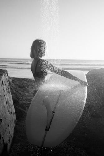 a person sitting on the beach with a surfboard at Samas Lasal - Hotel La Saladita in Temalhuacán
