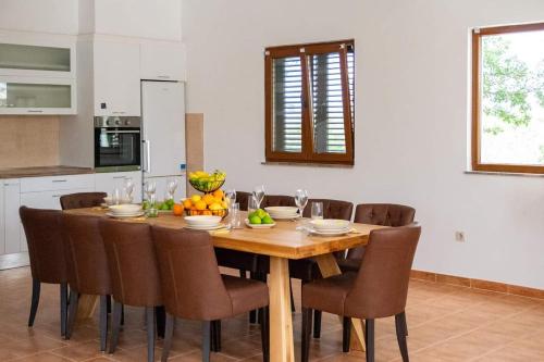 a kitchen with a wooden table with chairs and fruit on it at Family friendly house with a swimming pool Posedarje, Novigrad - 23578 in Posedarje