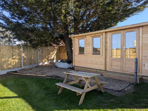 a picnic table in front of a wooden cabin at The Homestead Compact With private Lazy spa in Northbourne