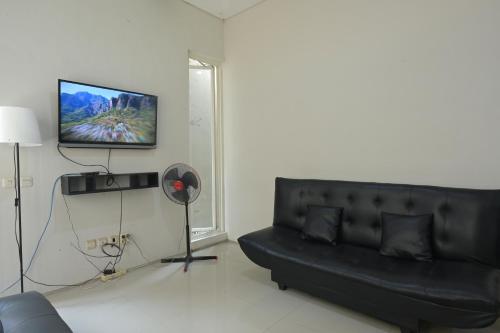 a living room with a black couch and a flat screen tv at GreenLake Vista in Surabaya